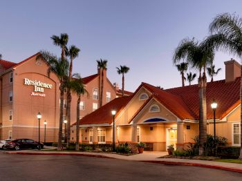A Residence Inn by Marriott hotel with red-tiled roofs, palm trees, and a parking area under a twilight sky.